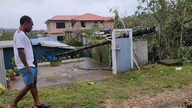 A man walks next to a fallen pole in the aftermath of cyclone Kevin, in Port Vila