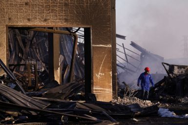 A man walks through the remnants of a warehouse which was burned during days of looting, in Durban