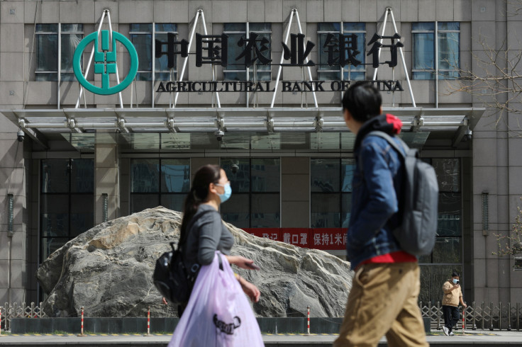 People walk past an office building of Agricultural Bank of China, in Beijing