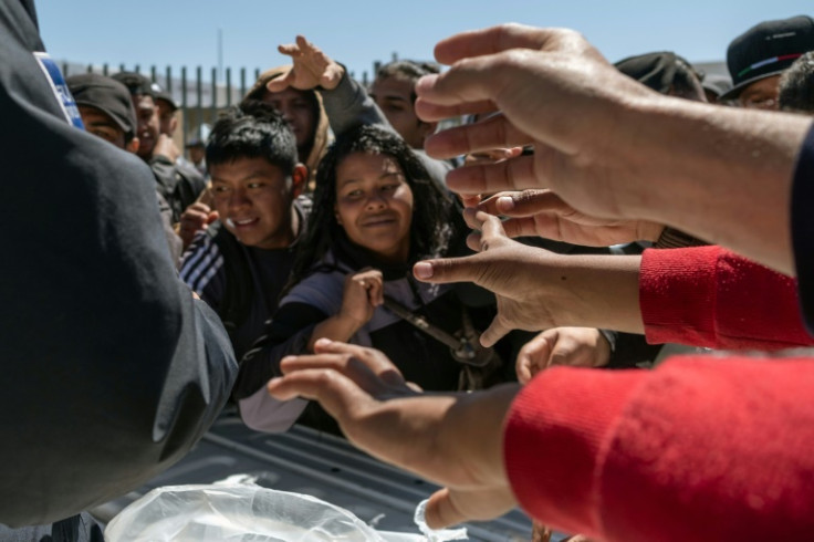 A police officer gives water to migrants outside the detention center where 39 migrants died in a fire