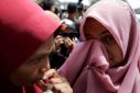 Former Malaysian Prime Minister Najib Razak's supporters wipe their tears at Putrajaya