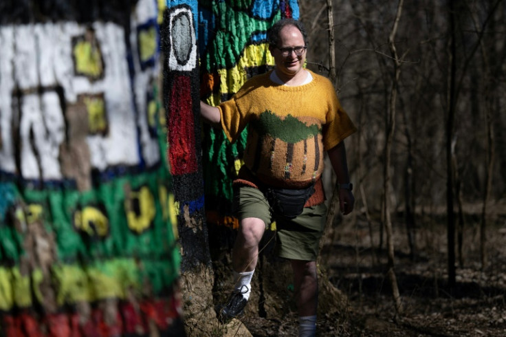 Sam Barsky poses in one of his nature-inspired sweaters in Oregon Ridge Nature Center, where he knitted during the pandemic