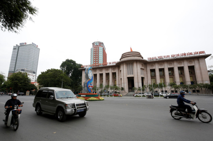 People go past the State Bank building in central Hanoi