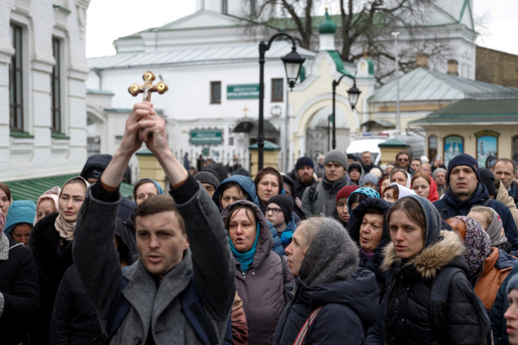 Believers pray while they block an entrance to a church at a compound of the Kyiv Pechersk Lavra monastery in Kyiv