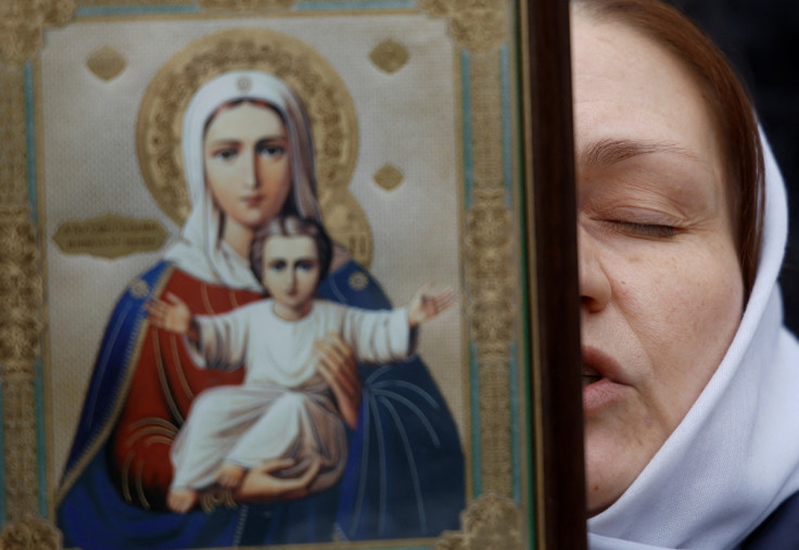 Believer prays while she blocks an entrance to a church at a compound of the Kyiv Pechersk Lavra monastery in Kyiv