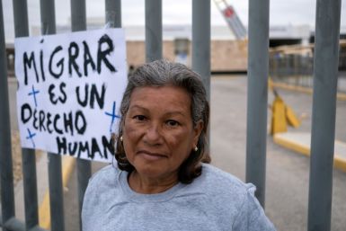 Luisa Jimenez from Venezuela stands next to a sign that reads: 'Migration is a human right'
