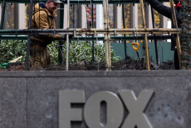 Workers clean up the burnt remains of a Christmas tree outside the News Corp. and Fox News building in New York
