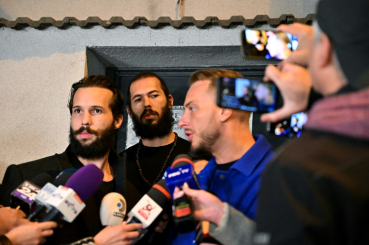 Andrew Tate (C) and his brother Tristan Tate (L) walk out of the central arrest centre of Bucharest police after three months of pre-trial detention