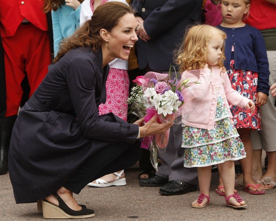 Catherine, the Duchess of Cambridge laughs after receiving flowers from Alexa Currie during visit to Summerside