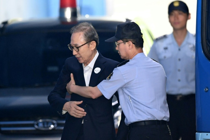 Former South Korean president Lee Myung-bak is helped by a prison official as he arrives at a court to attend his trial in Seoul on September 6, 2018