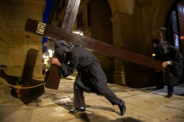 A penitent bears a cross during an Easter Week procession on Maundy Thursday, 2022