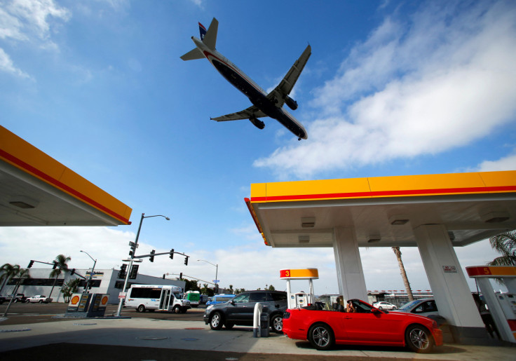 Consumers purchase gasoline at a gas station as a plane approaches to land at the airport in San Diego