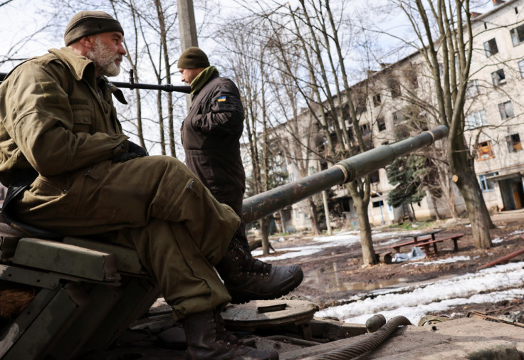 Ukrainian servicemen stand atop a tank, near the bombed-out eastern city of Bakhmut