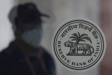 A man walks behind the Reserve Bank of India (RBI) logo inside its headquarters in Mumbai