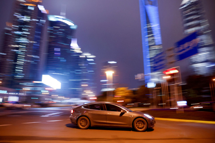 A Tesla electric car drives past a crossing in Shanghai