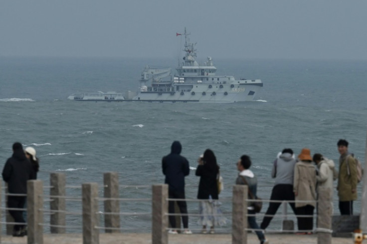 A PLA Navy tugboat sails past tourists on Pingtan island, China's nearest point to Taiwan, on Friday