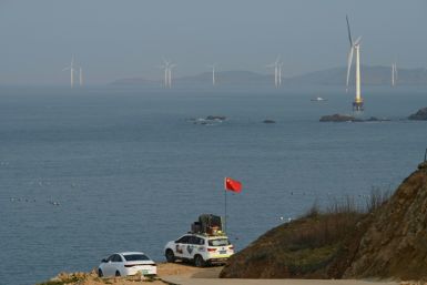 A man sets up a Chinese flag on his car as he prepares to look at the view of the Taiwan Strait towards the zone where China said it would conduct live-fire exercises