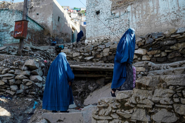 Burqa-clad Afghan women climb a stony path to their homes in the Shor Bazar area of the capital