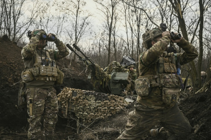 Ukrainian servicemen look through binoculars next to an anti-air gun near Bakhmut in the eastern Donetsk region