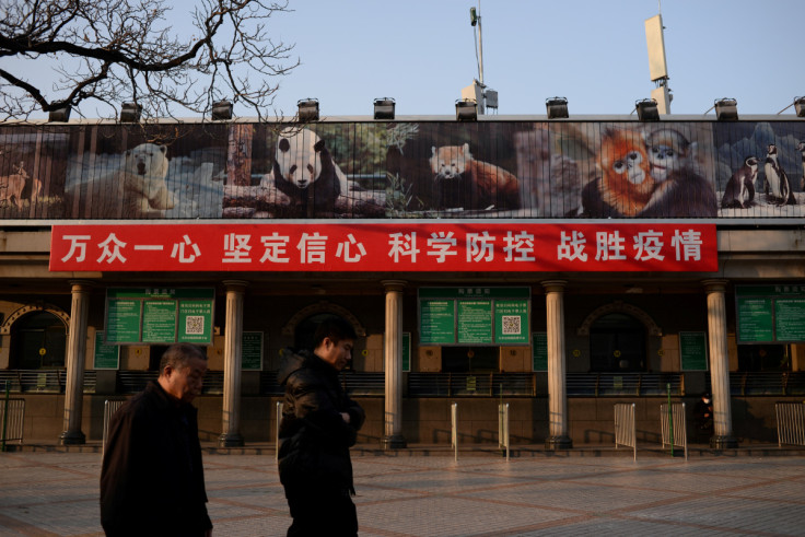 Men walk past a banner hung on the ticket office of the Beijing Zoo that is closed following an outbreak of the novel coronavirus in the country, in Beijing