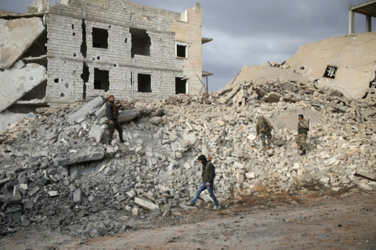 Syrian rebel fighters walk through the rubble of a building destroyed in the countryside of western Aleppo, on November 26, 2018