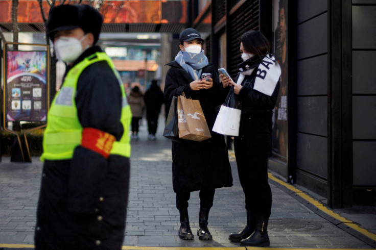 Women with shopping bags stand in a street as China returns to work despite continuing coronavirus disease (COVID-19) outbreaks in Beijing