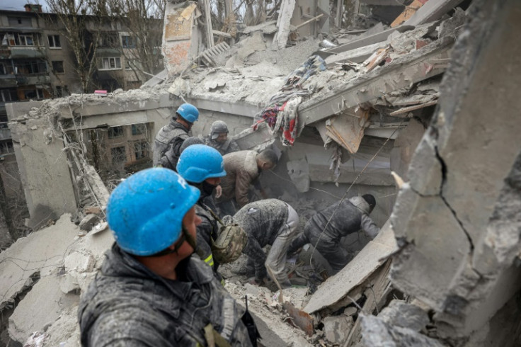 Rescuers and volunteers look for survivors on the top of a partially destroyed residential building