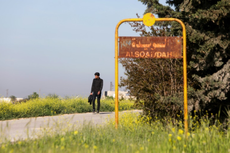 A man walks past the sign of Al-Suwaydah village near Jarablus in Syria's Aleppo province after the US helicopter raid