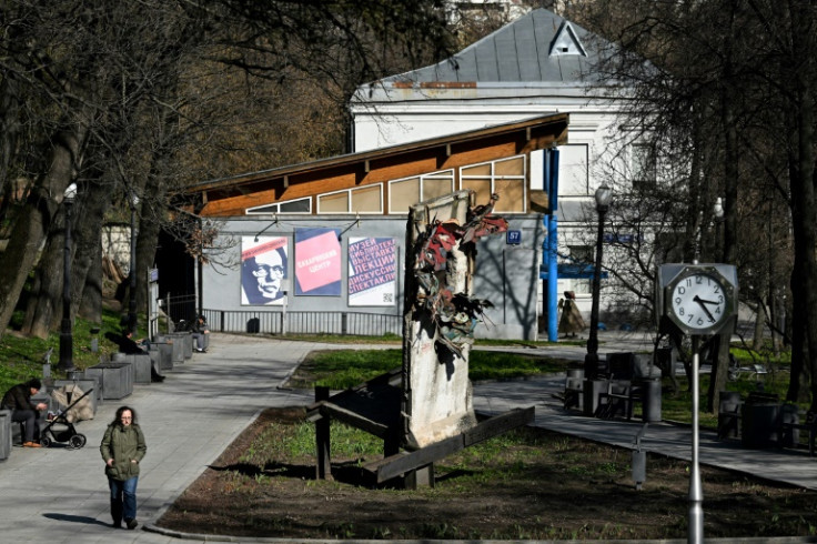 A woman walks past a piece of the Berlin Wall installed in front of the Andrei Sakharov Museum and Public Centre in Moscow