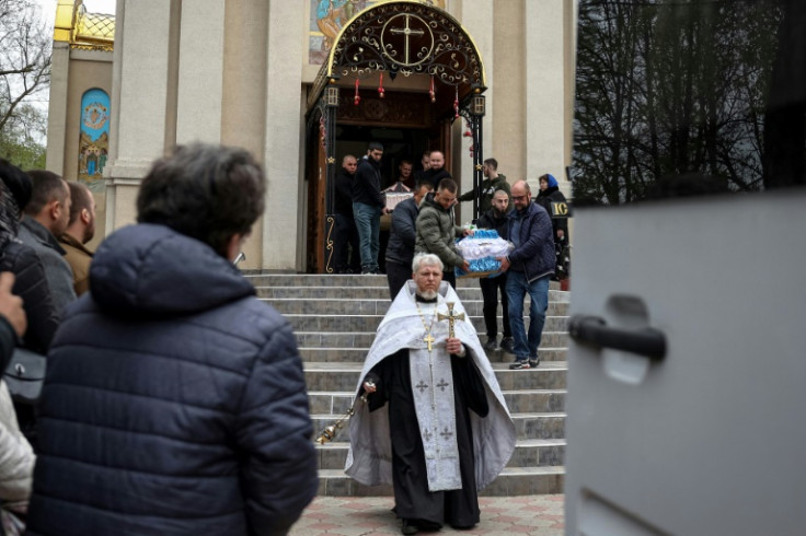 An Orthodox priest leads the funeral procession of Maksym, 2, and his father Sergei Komarista, 29, in Sloviansk