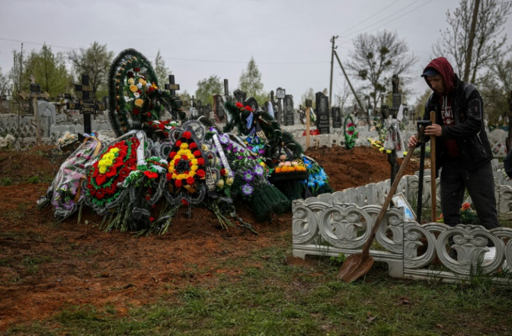 A cemetery employee stands next to graves of two-year-old Maksym and his father Sergei Komarista after their burial in Sloviansk