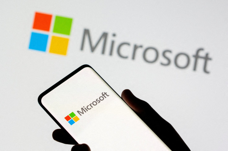 Smartphone is seen in front of Microsoft logo displayed in this illustration taken