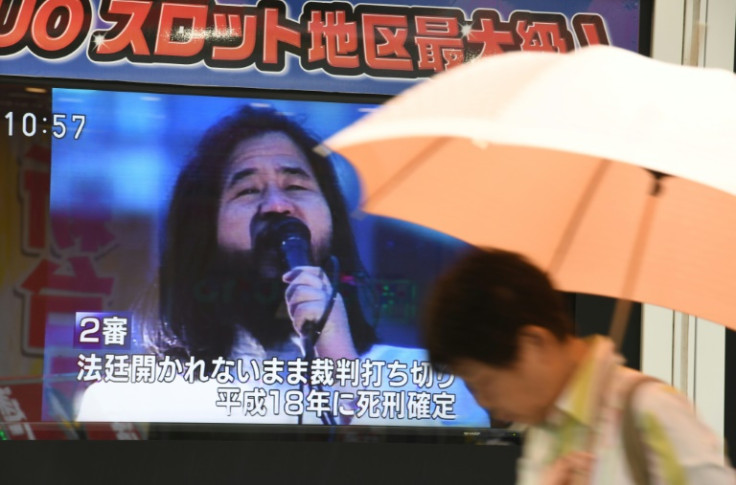 A pedestrian walks past a screen flashing news on the execution of Shoko Asahara, the leader of the Aum Shinrikyo cult, in Tokyo on July 6, 2018. Shoko Asahara, the leader of the Aum Shinrikyo cult that carried out a deadly sarin attack on Tokyo's subway