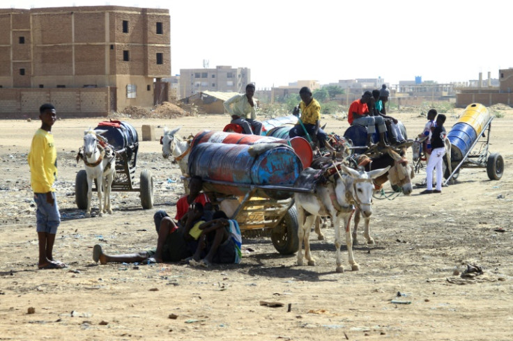 People fill barrels with water in southern Khartoum on April 22, 2023, amid water shortages caused by ongoing battles