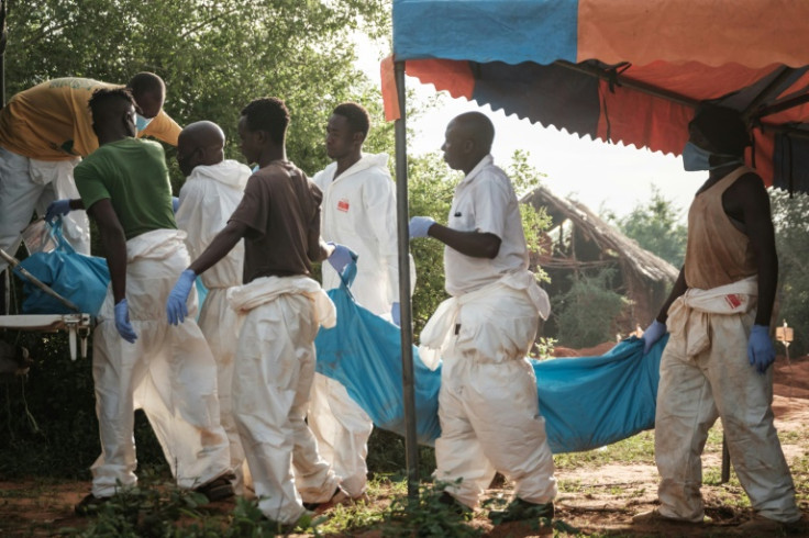 Workers carry the exhumed bodies in bodybags to the mortuary, at the mass grave site in Shakahola