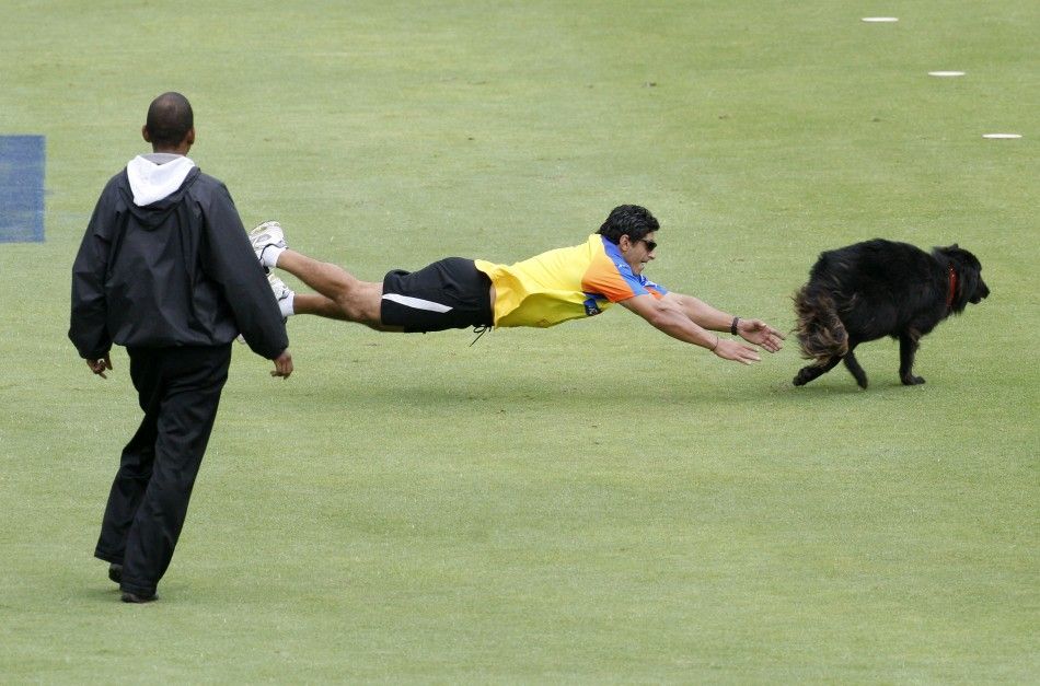 An official attempts to catch a dog that disrupted play in the opening game of IPL T20 cricket tournament between the Mumbai Indians and Chennai Super Kings in Cape Town