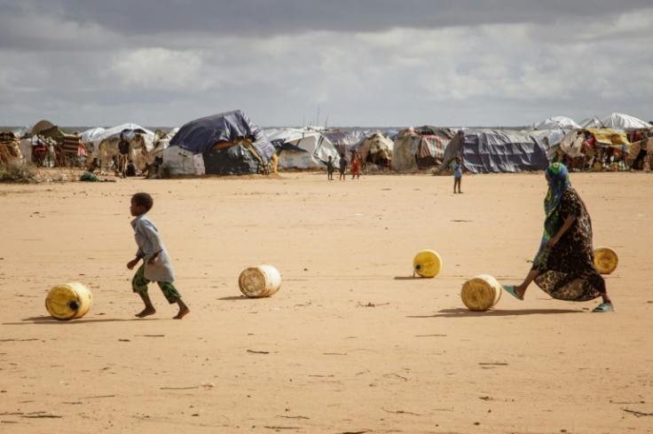 Somali refugee children roll water containers as they bring them back to their makeshift shelter in the Dadaab refugee camp