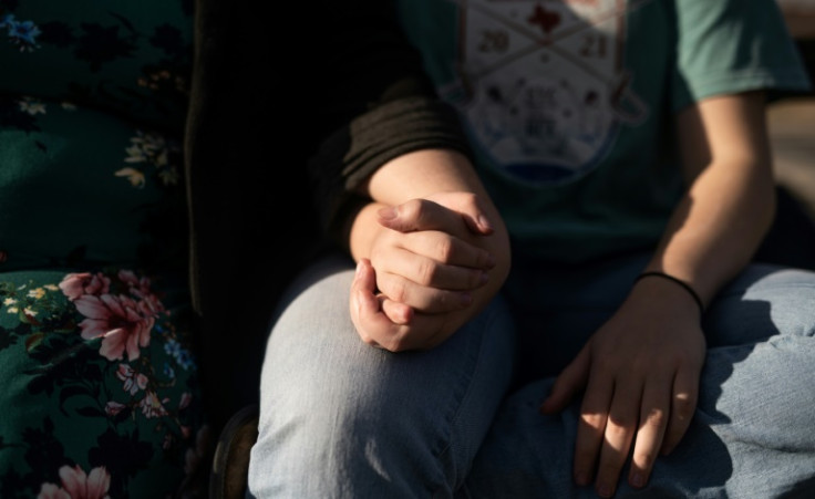 Mary and her teenage child Jasper (these are pseudonyms) clasp hands in a public park in Minneapolis, where they moved from Texas to ensure Jasper's safety amid anti-transgender bias
