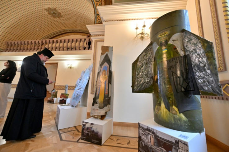 An Orthodox priest looks at a creation made out of Russian missile fragments
