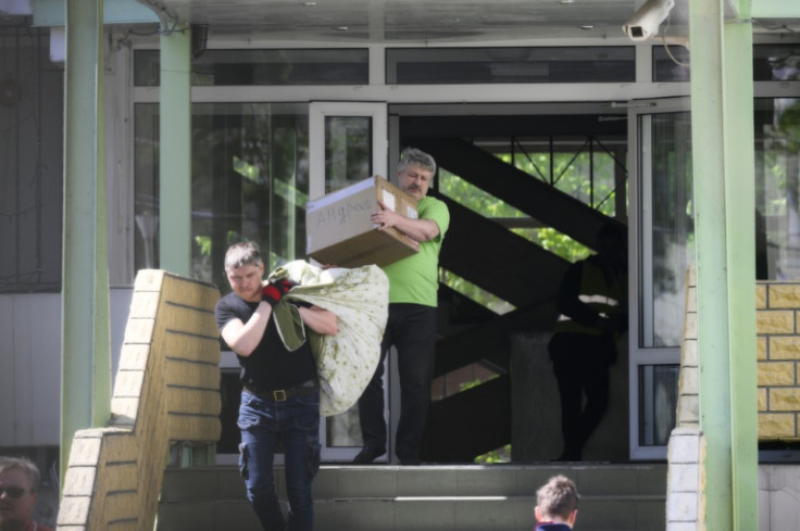 Men carried a bag and a box with a Cyrillic text written on it from the site of the Russian high school