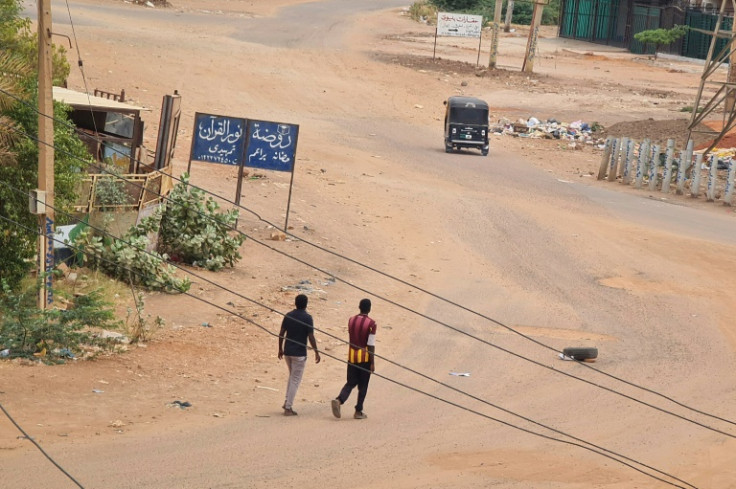 People walk on a deserted street in Khartoum on April 30, 2023, as clashes continue in war-torn Sudan