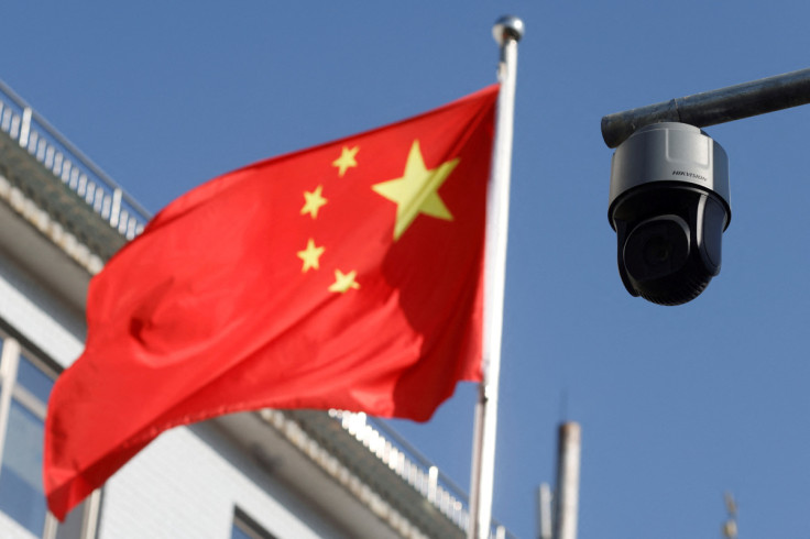 A security surveillance camera overlooking a street is pictured next to a nearby fluttering flag of China in Beijing