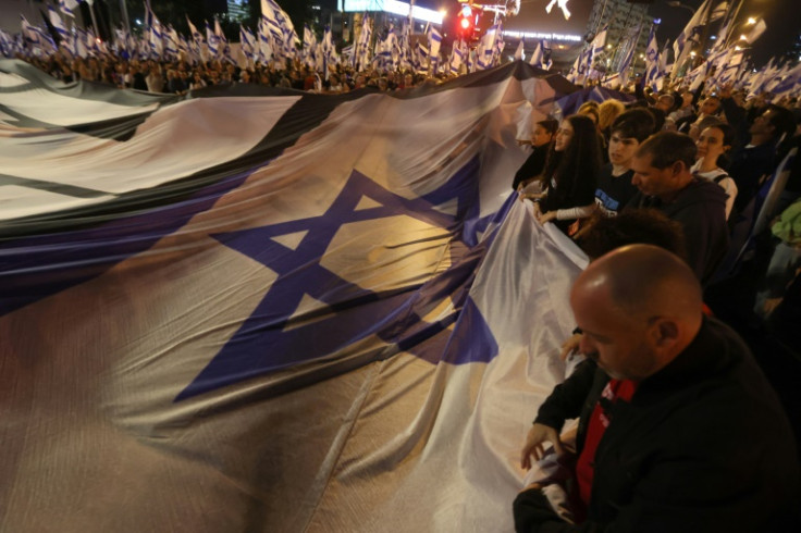 Demonstrators lift a large national flag during a rally to protest the Israeli government's judicial overhaul bill in Tel Aviv, on April 29, 2023