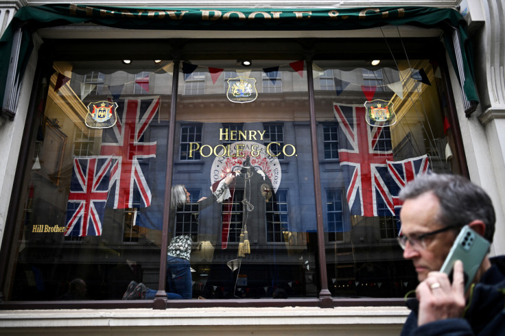 A worker adjusts the window display of Henry Poole tailors on Savile Row, ahead of the Coronation in London