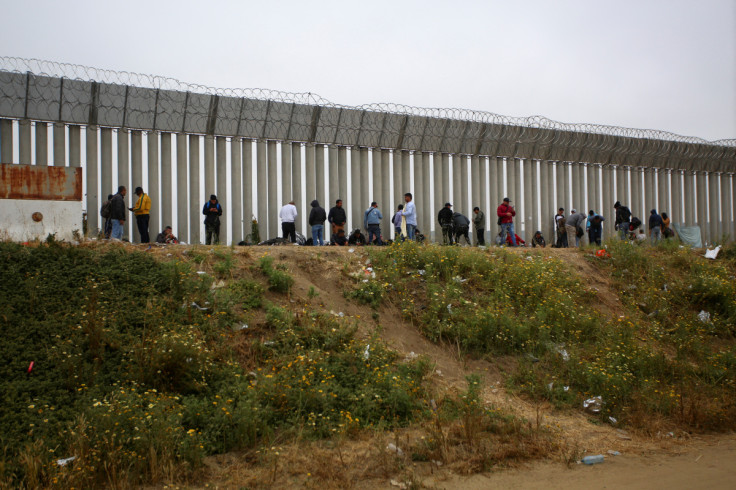 Migrants reach the border to request asylum to U.S. authorities between the two border fences, in Tijuana