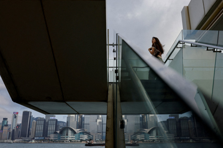 A mainland Chinese tourist looks out at the skyline of buildings at Tsim Sha Tsui, in Hong Kong