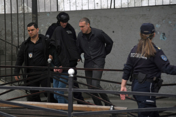 Police officers walk with a shooting suspect out of school after he opened fire on other students and staff at a school in Belgrade