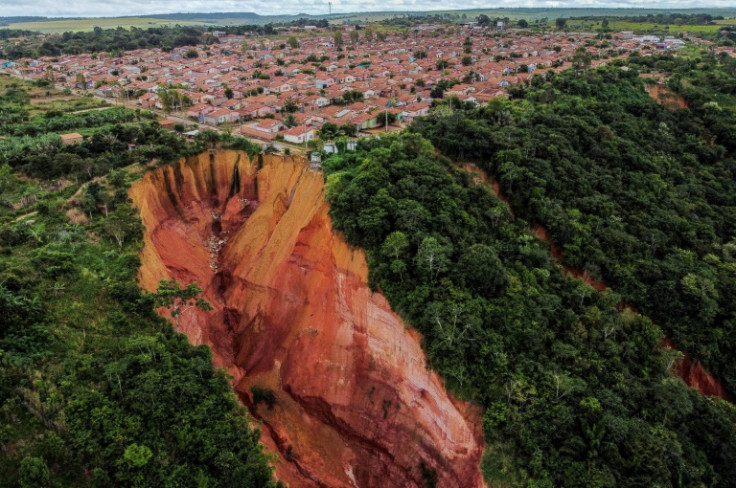 Seen from the sky, the craters look like big red- and orange-hued canyons swallowing pieces of the city as they advance