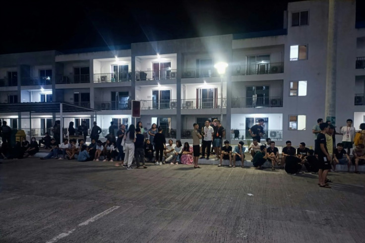 The rescued workers stand outside a building after a police raid in Mabalacat in the Philippine province of Pampanga