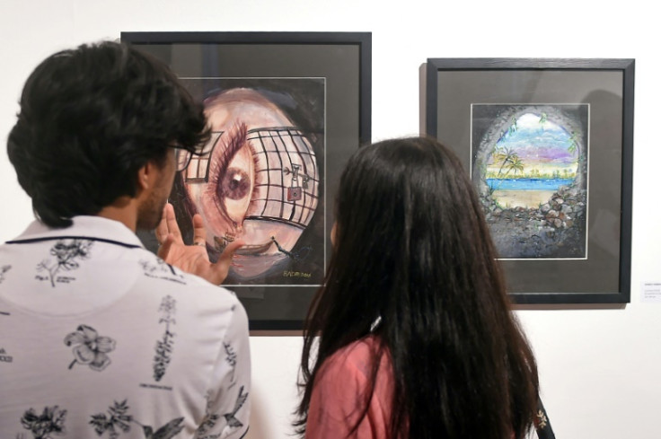Visitors look at paintings made by Ahmed Rabbani, a Pakistani recently freed from Guantanamo Bay prison, during an exhibition of his work in Karachi